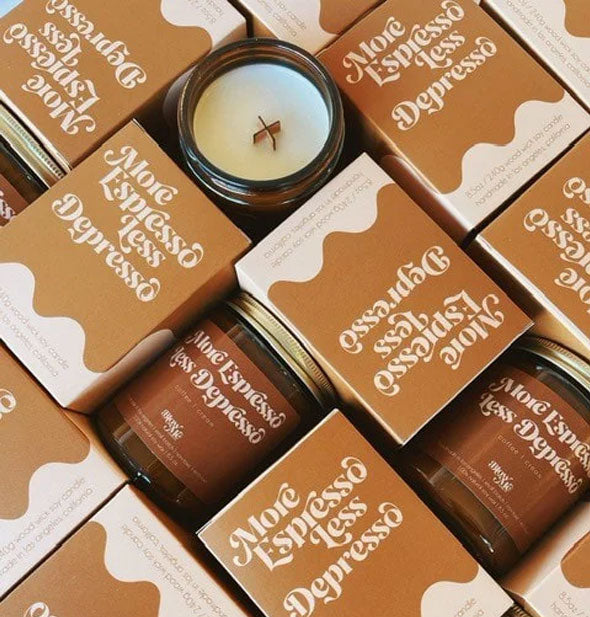 Collection of More Espresso Less Depresso candle jars and boxes; one candle's wooden X-shaped wick is visible