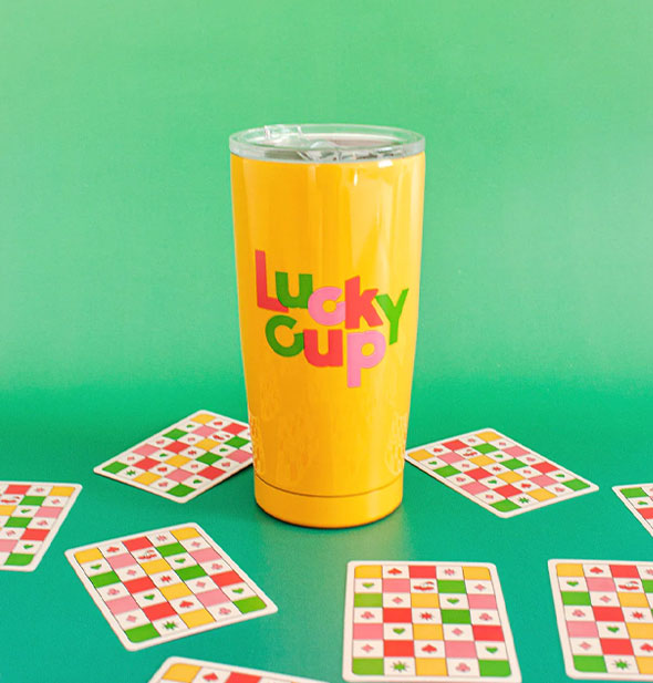 Lucky Cup tumbler is staged with checker print playing cards on a green backdrop