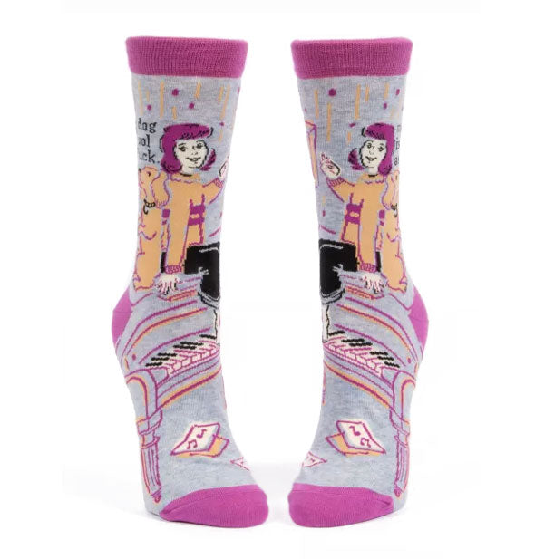 Gray crew socks with pink top band, heel, and tow feature all-over illustration of a woman and her dog sitting on top of a piano next to the words, "My dog is cool as fuck" in black lettering