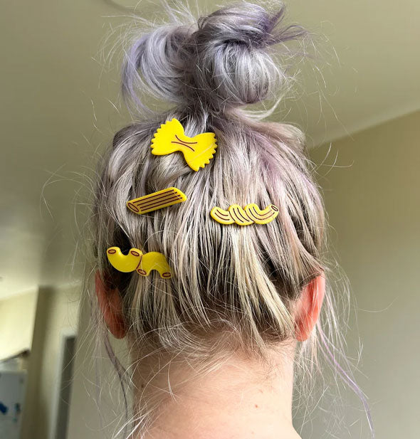 Model wears for pasta-shaped hair clips on the underside of a topknot