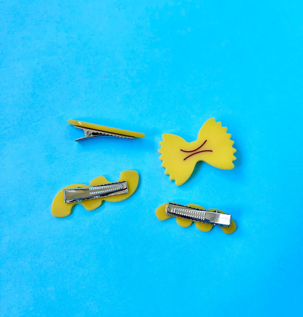 Four noodle hair clips, all but bowtie turned over to show their metallic hardware