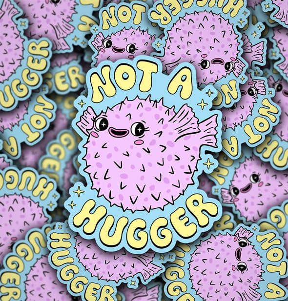 Pile of stickers with smiling spiny purple blowfish illustration say, "Not a Hugger" in yellow lettering