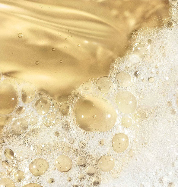 Closeup of golden cleansing oil partially foamed