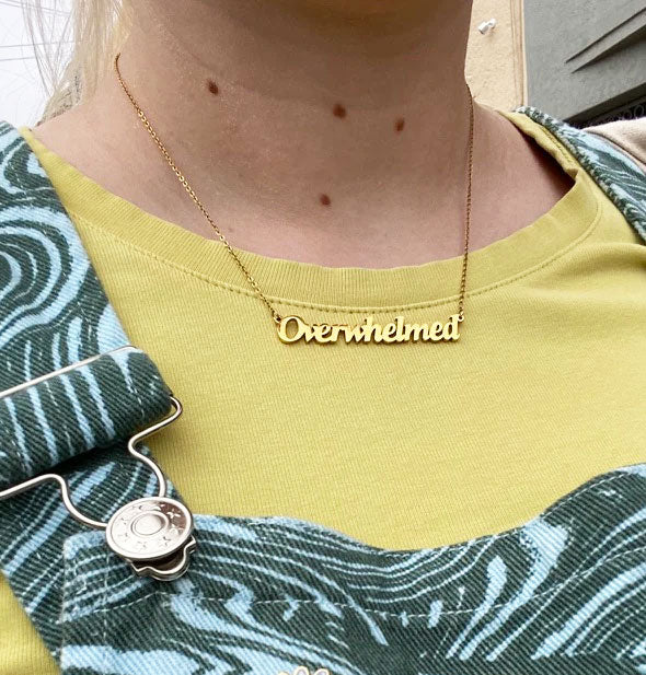 Model wears a gold Overwhelmed nameplate necklace