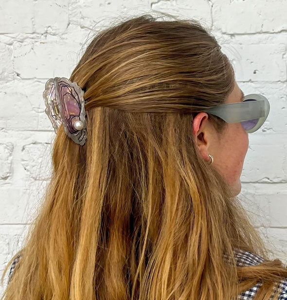 Model wears a hair clip designed to resemble an oyster shell with a pearl inside