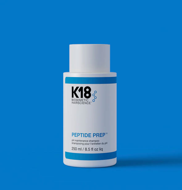 White 8.5 ounce bottle of K18 Biomimetic Hairscience Peptide Prep pH Maintenance Shampoo on a blue backdrop