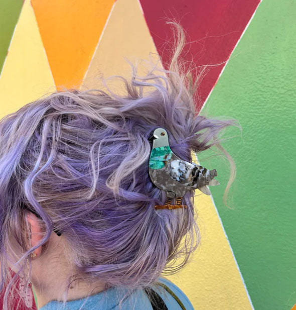 Model wears a pigeon claw clip in a swept-up hairstyle