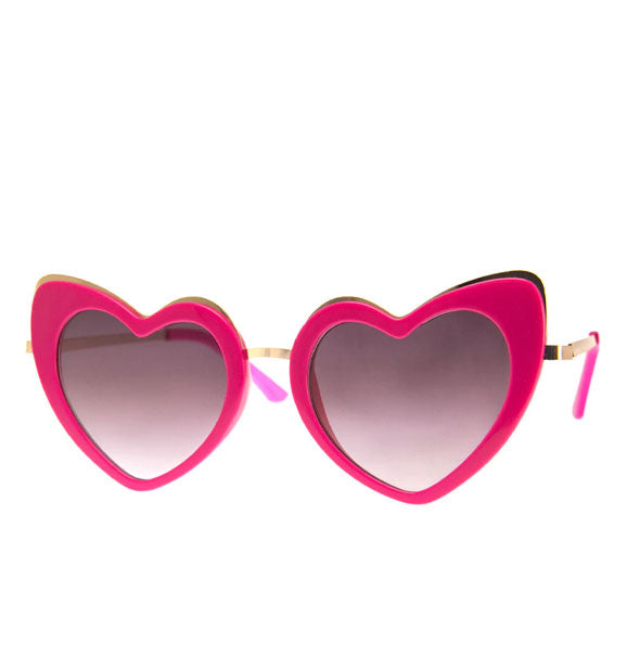 Pair of pink heart-shaped sunglasses with gold details and pink temple tips