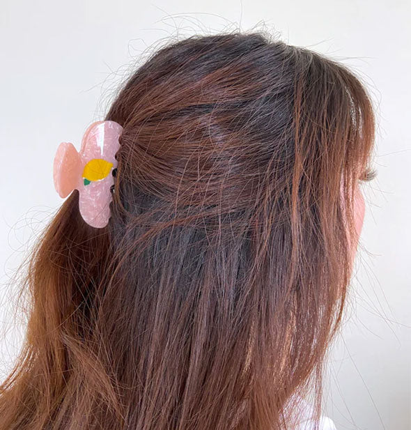 Model wears a pink lemon claw clip in a partially swept-back hairstyle
