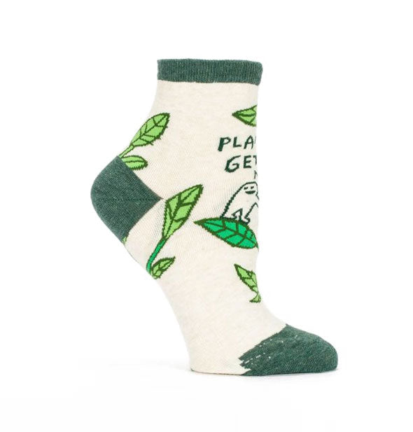 Socks with illustration of cartoon character watering a large houseplant say, "Plants get me."