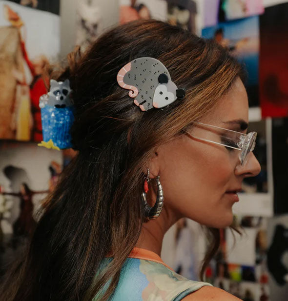 Model wears a possum clip at the side of hair that is secured at the back with a racoon in trash can claw clip