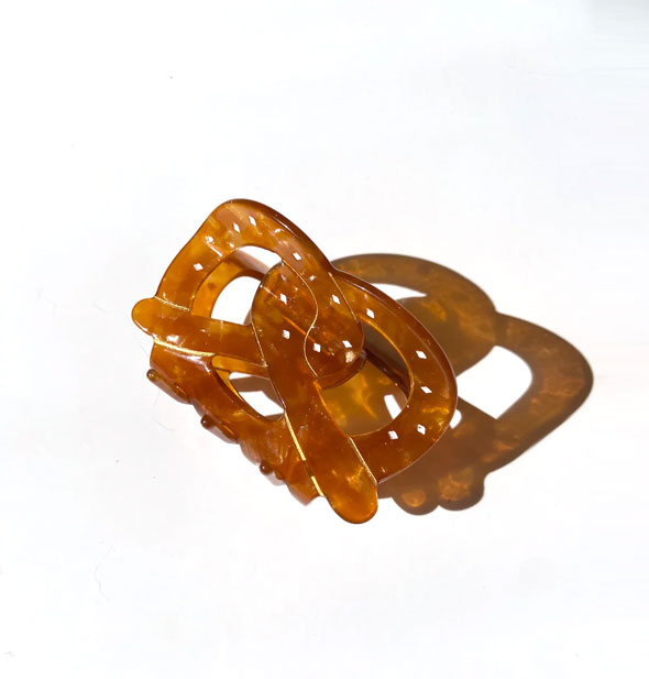 Brown translucent hair clip resembles a pretzel with white flecks of hand-painted salt detail