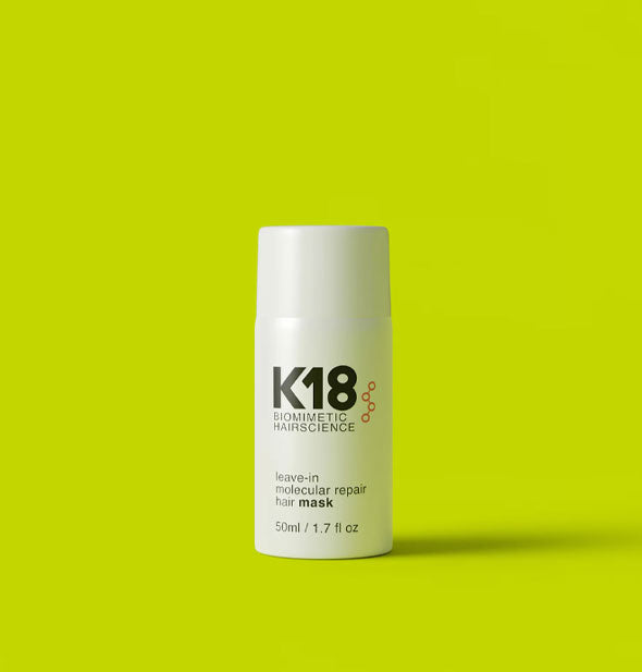 White 1.7 ounce bottle of K18 Biomimetic Hairscience Leave-in Molecular Repair Hair Mask on a bright lime green background
