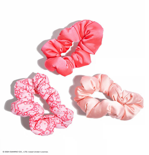 One dark pink, one pink Hello Kitty face print, and one light pink puffy satin-like hair scrunchies