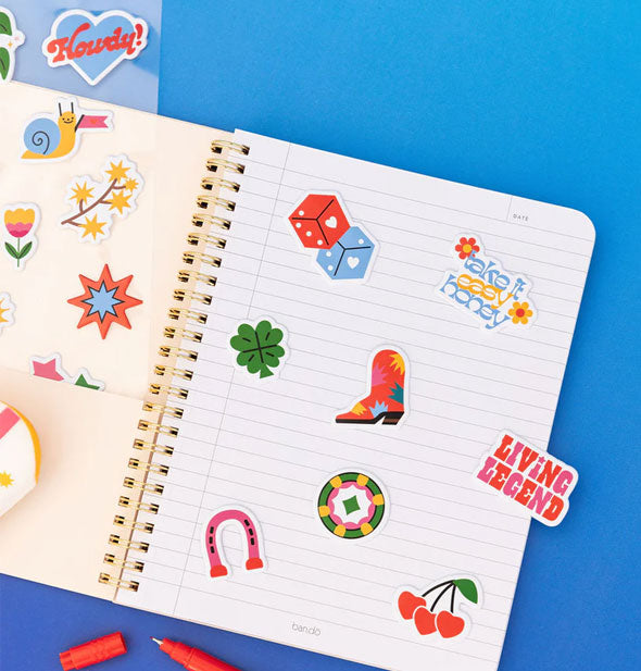 A notebook page is littered with colorful stickers