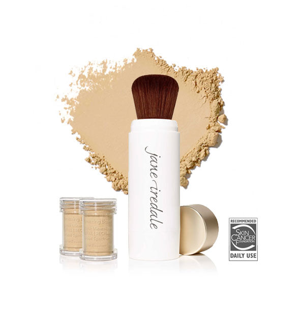 White Jane Iredale powder brush with gold cap removed and set to the side, two refill canisters nearby, and an enlarged product sample in the background in shade Radiant