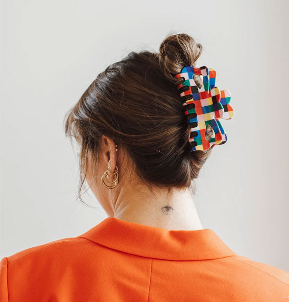 Model wears a multicolored checker print hair claw around a twist updo