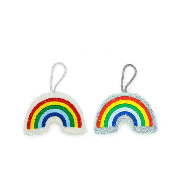 Pair of sponges designed to resemble rainbows with stripes of red, yellow, green, light blue, and dark blue lined with white and gray textured material respectively and each with a nylon hanging strap at the top