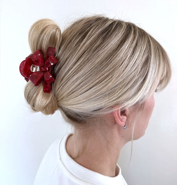 Model wears a red bow claw clip in a twisted updo