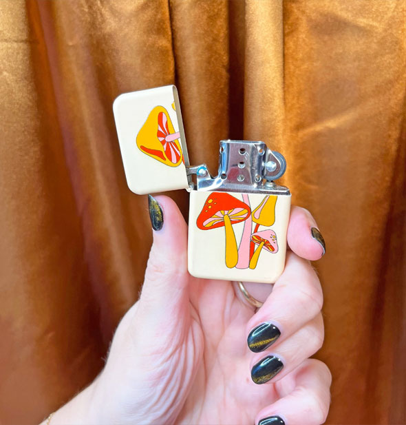 Model's hand holds an opened mushroom lighter against a bronze cloth backdrop