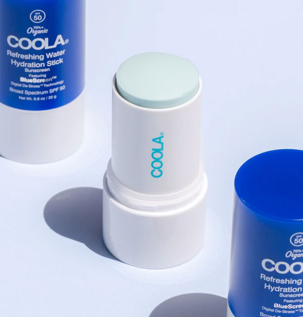 Tubes of Coola Refreshing Water Hydration Stick Sunscreen, the center one with cap removed to show product