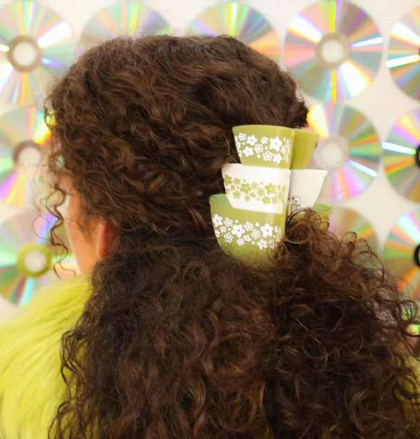 Model wears a claw clip designed to resemble a stack of three green and white retro Pyrex bowls with daisy print in a half-up hairstyle