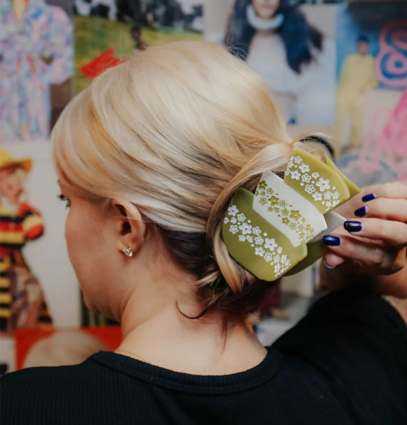 Model wears a claw clip designed to resemble a stack of three green and white retro Pyrex bowls with daisy print in a swept-back hairstyle