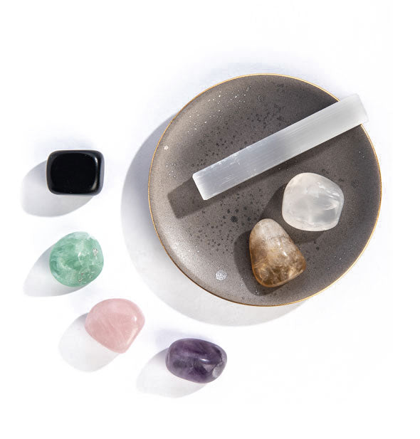 Contents of the Fresh Start Ritual Kit: ceramic dish, selenite wand, and polished amethyst, fluorite, rose quartz, citrine, black obsidian, and clear quartz stones