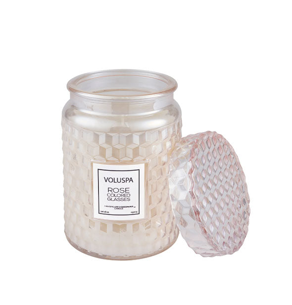 Pearlescent rosy-gold textured Voluspa Rose Colored Glasses candle jar with matching lid removed and propped up alongside