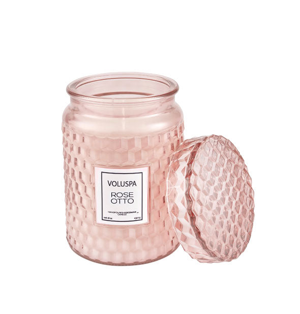 Voluspa Rose Otto textured pink glass candle jar with lid removed and propped up alongside