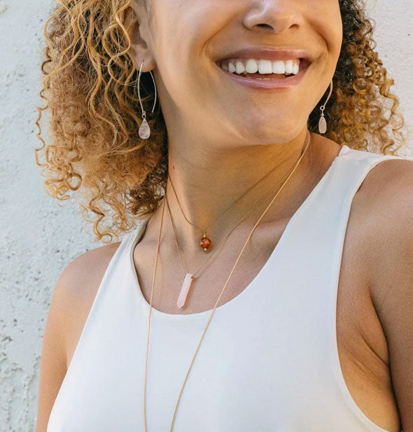 Smiling model wears a rose quartz point necklace with other accessories