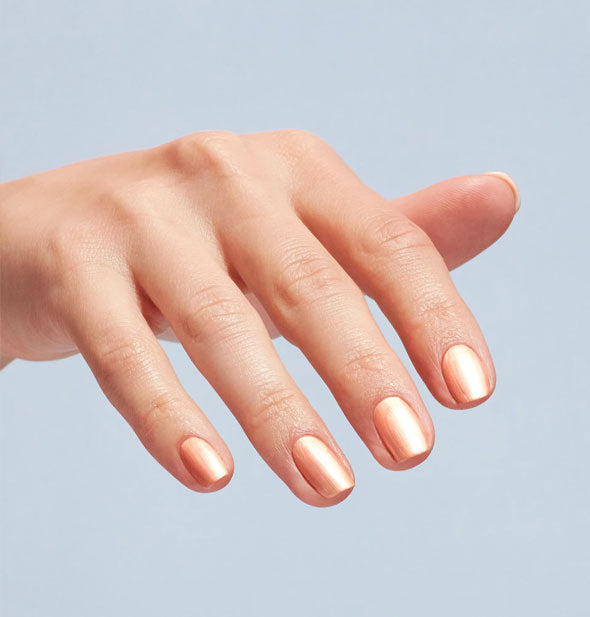 Model's fingernails are painted with a light shimmery orange nail polish