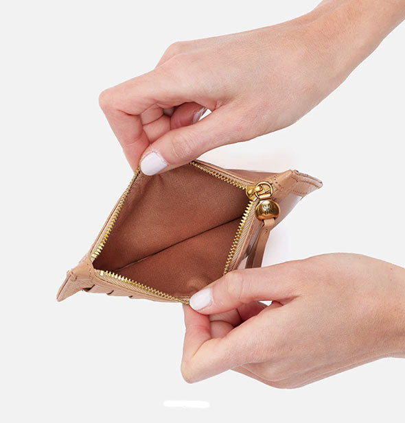 Model's hands hold open a tan leather card case wallet with brown interior and gold zipper hardware