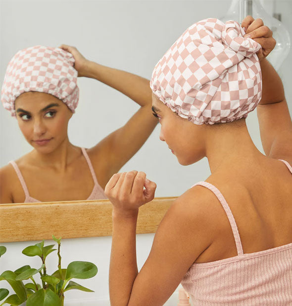 Model secures a checkered shower cap at the back of head