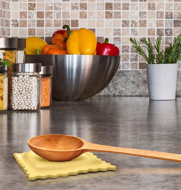 Ravioli rest holds a wooden spoon on a kitchen countertop