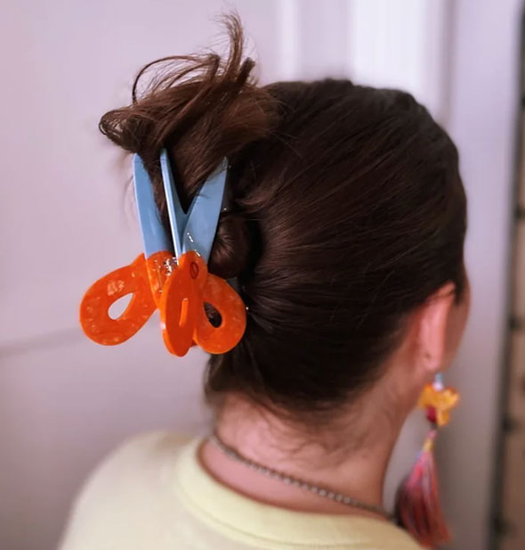 Model wears a scissors hair claw in a swept-back style