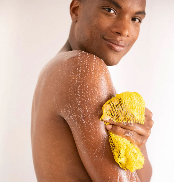 Smiling model uses a Fur Scrub Sheet on upper arm with a light soap lather