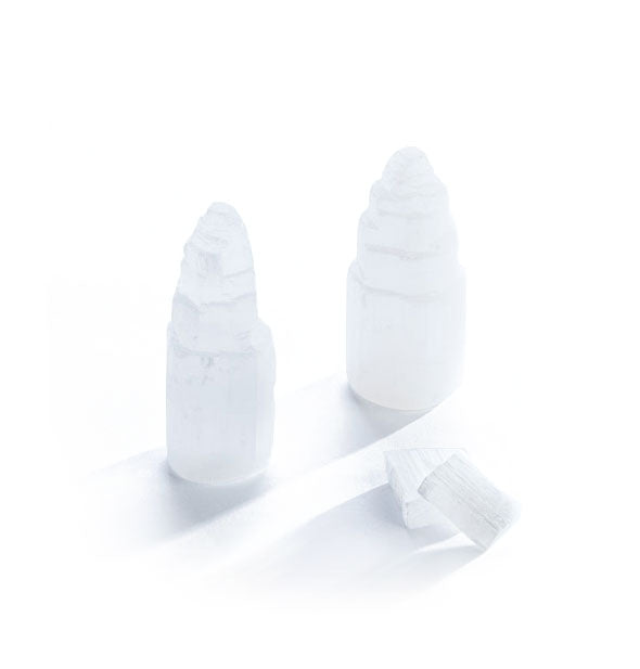 Two selenite crystal towers with tiered tops sit alongside two other pieces of selenite