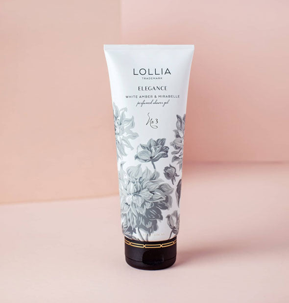 White tube of Lollia Elegance White Amber & Mirabelle Perfumed Shower Gel with lush grayscale floral design and a dark cap accented by gold