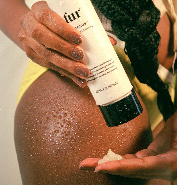 Model dispenses a dollop of Fur Silk Scrub into hand in front of their water droplet-covered knee