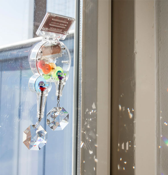 RainbowMaker attached to a sunny window pane throws prisms across nearby surfaces