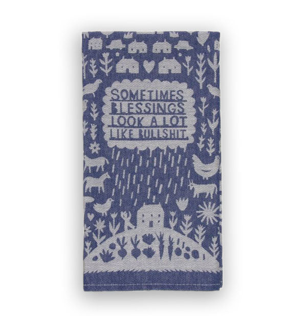 Blue dish towel with all-over illustrations of farm animals, hearts, flowers, and houses says, "Sometimes blessings look a lot like bullshit" in a central raincloud pouring down onto a house on a hill in which vegetables represent a garden