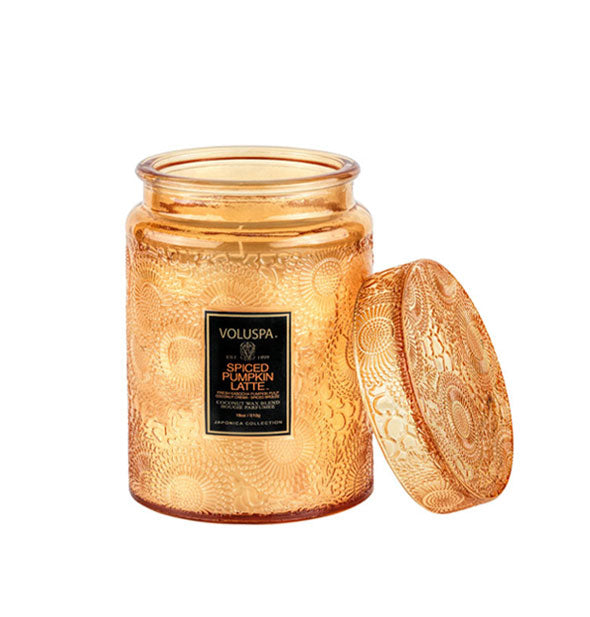 Orange embossed glass Voluspa Spiced Pumpkin Latte candle jar with matching lid removed and propped up alongside