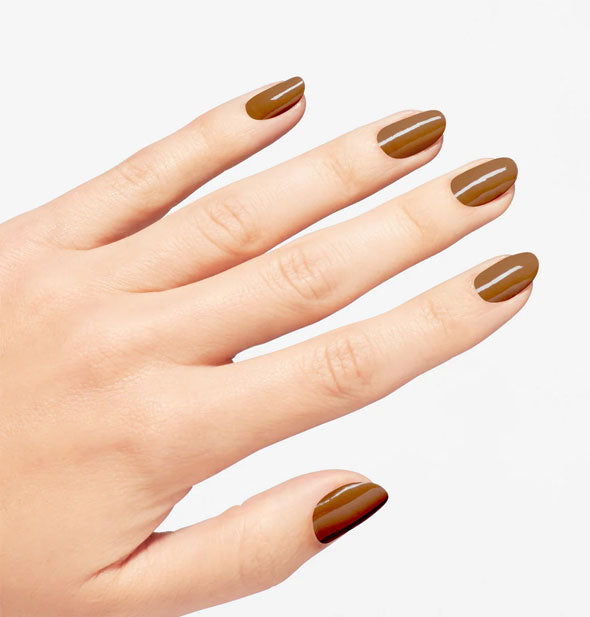 Model's hand wears a medium caramel-like shade of brown nail polish