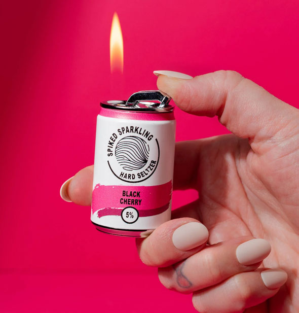 Model's hand holds a lit Black Cherry Spiked Sparkling Hard Seltzer lighter in front of a dark pink backdrop