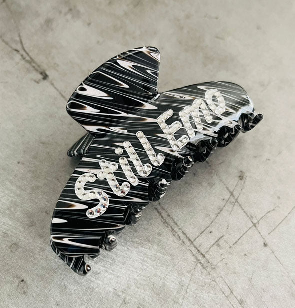 Black and white streaked claw clip says, "Still Emo" in white lettering accented with clear rhinestones