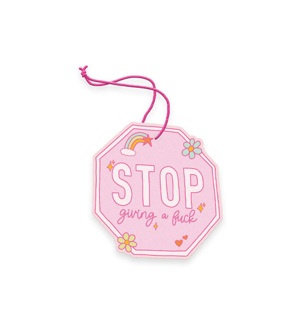 Pink air freshener on pink string resembles a traffic stop sign with rainbow, heart, star, and flower accents and says, "STOP giving a fuck"