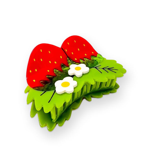 Hair clip designed to resemble two strawberries with green leaves and white flowers with yellow centers