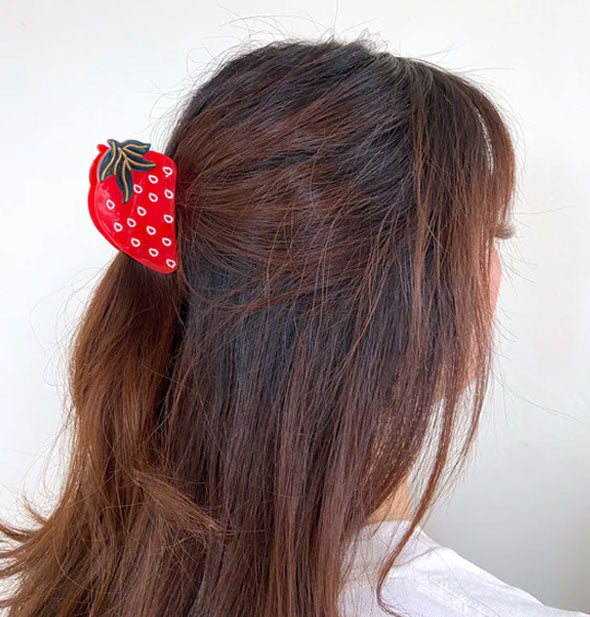 Model wears a red and green strawberry hair clip in a partially swept-back style