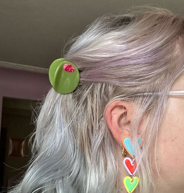 Model wears a green olive claw clip in a partially swept-back hairstyle
